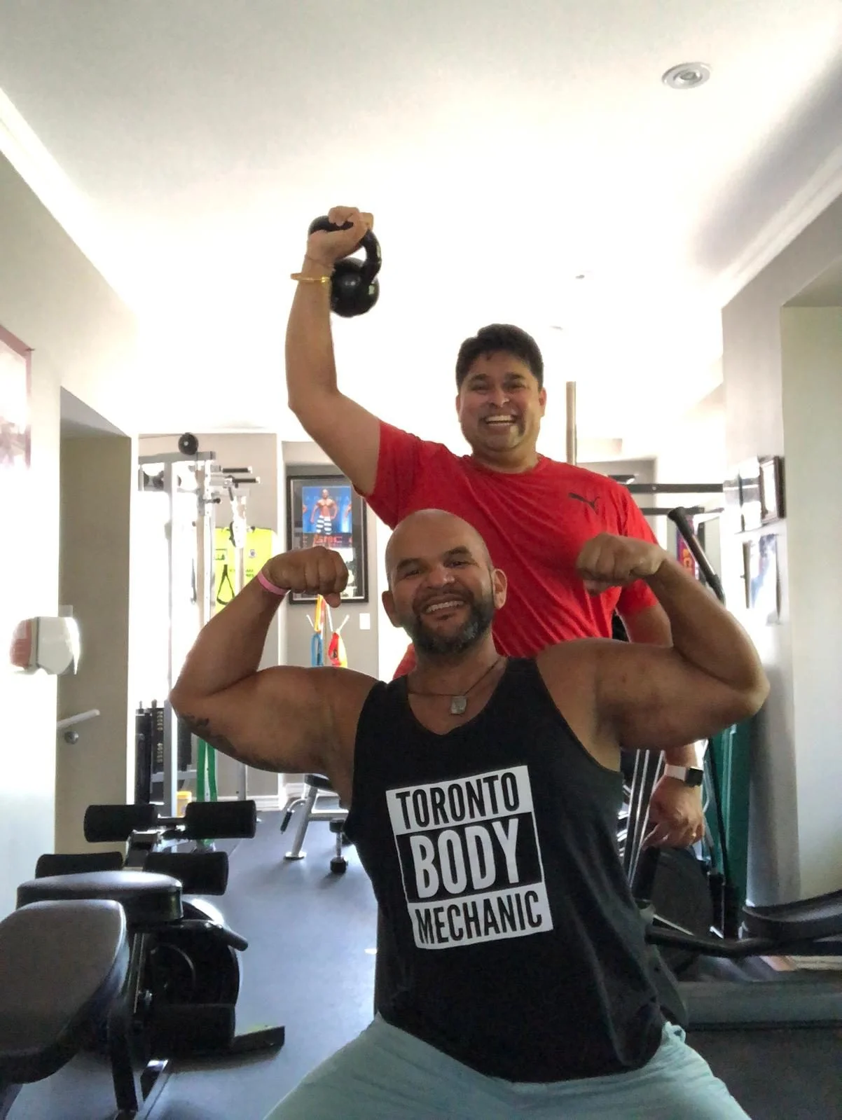 Ernesto Castillo with a training partner holding a kettlebell at the studio
